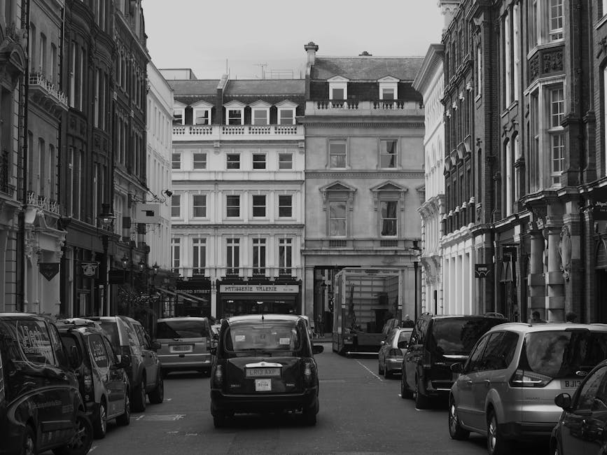 A detailed view of a historic building with ornate architectural features and a domed roof, located on a busy street. In front of the building, there is a red and white London Underground sign indicat
